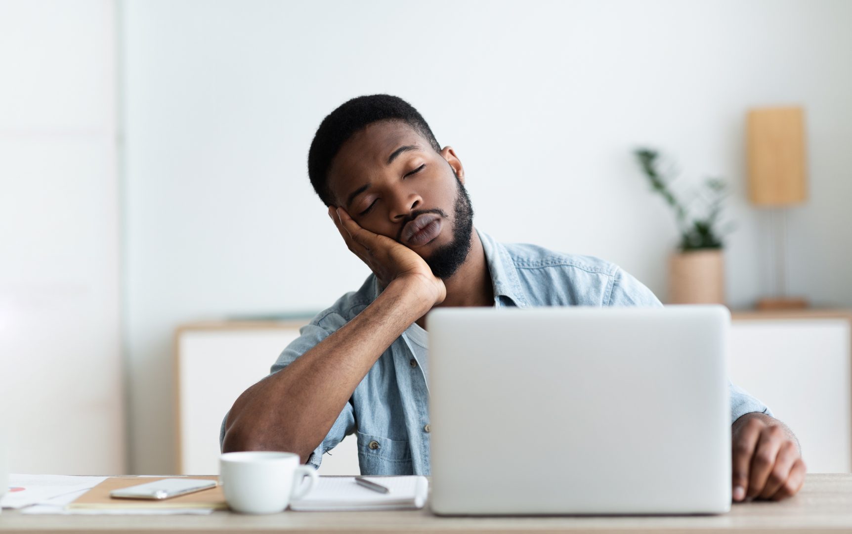 African american man with Chronic Fatigue Syndrome falling asleep at his work computer